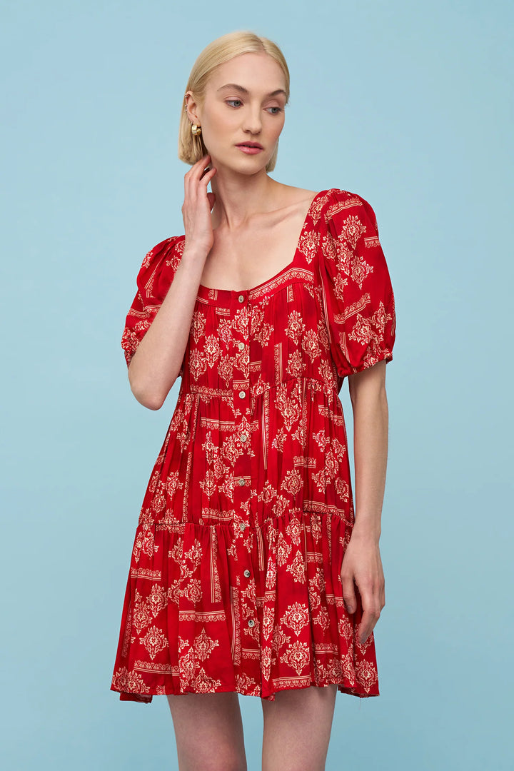 Woman wearing a red dress with white patterns against a light blue background