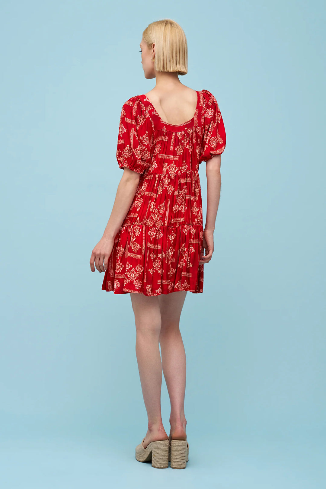 Woman wearing a red dress with puff sleeves on a light blue background