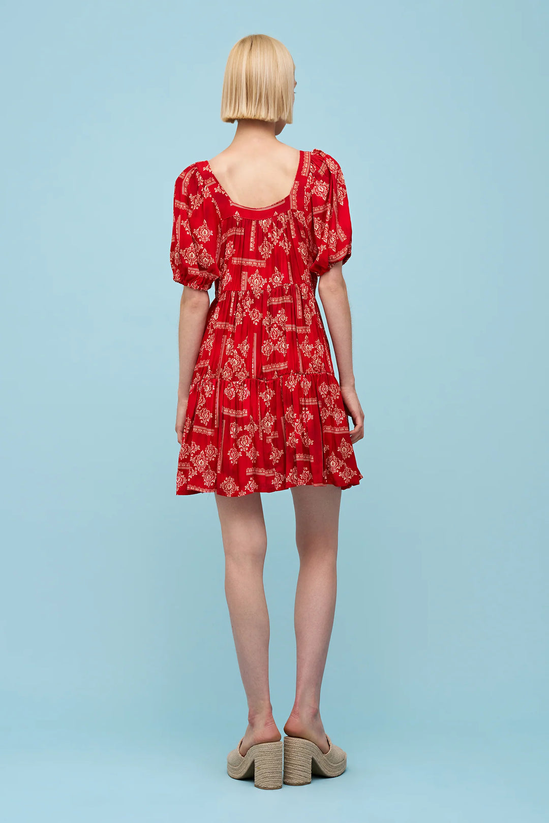 Person wearing a red dress with puff sleeves on a light blue background