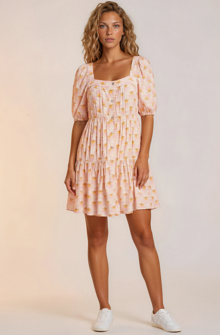 Woman wearing a pink patterned dress with puff sleeves against a plain background
