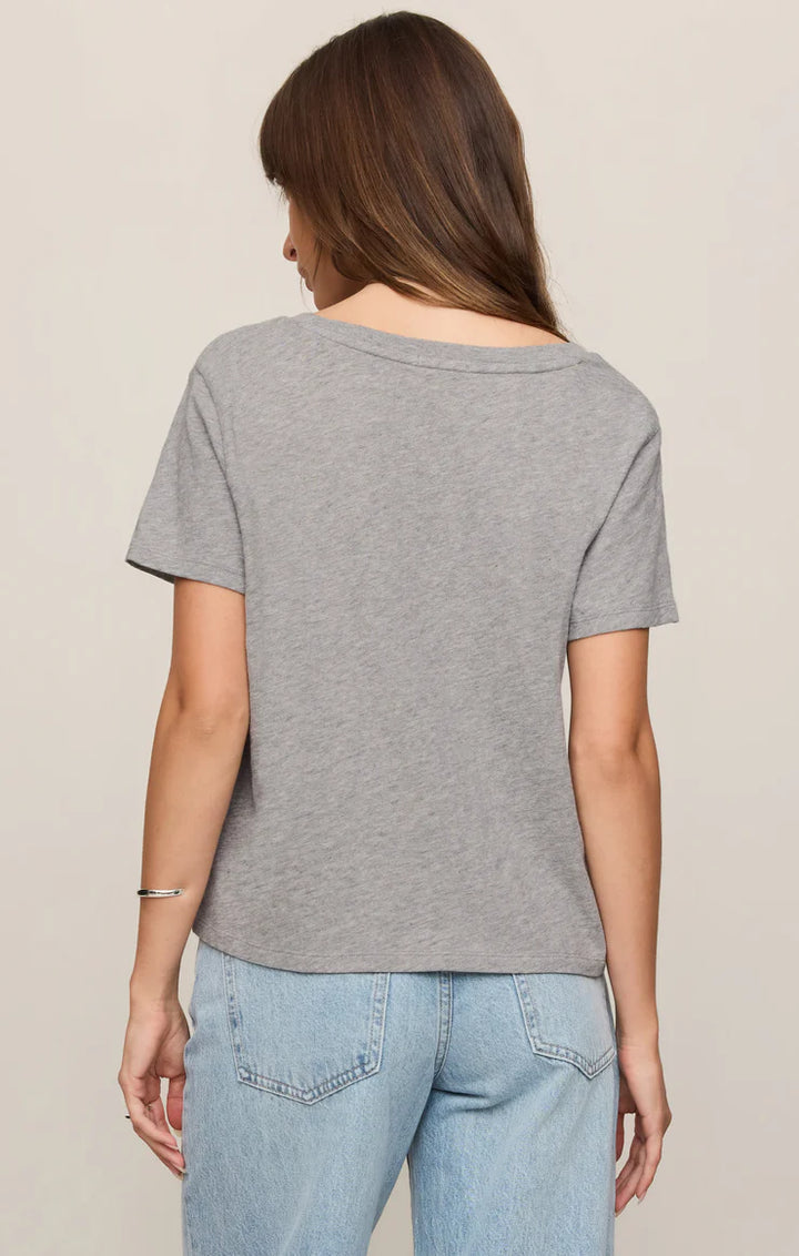 Person wearing a gray t-shirt and light blue jeans on a beige background