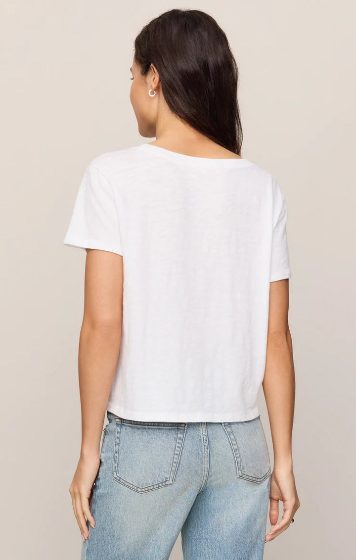 Person wearing a white t-shirt and light blue jeans on a beige background