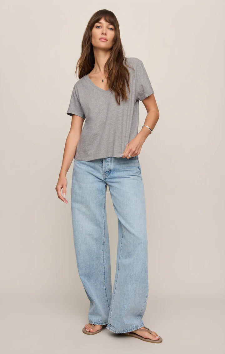 Woman wearing a gray t-shirt and light blue jeans on a beige background