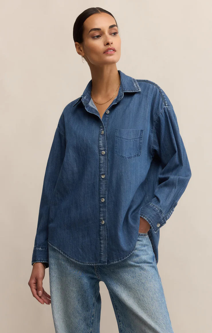 Woman wearing a blue denim shirt and jeans on a beige background