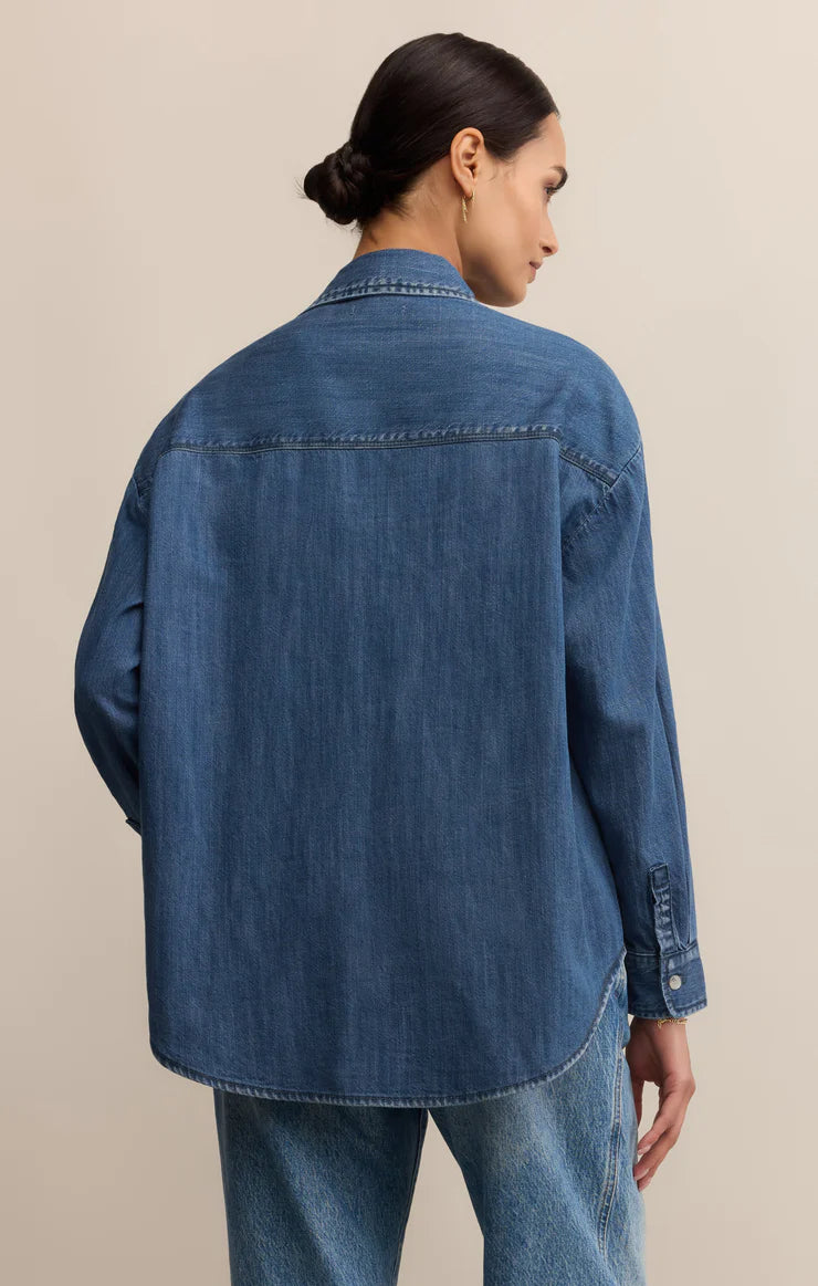 Person wearing a blue denim jacket on a beige background
