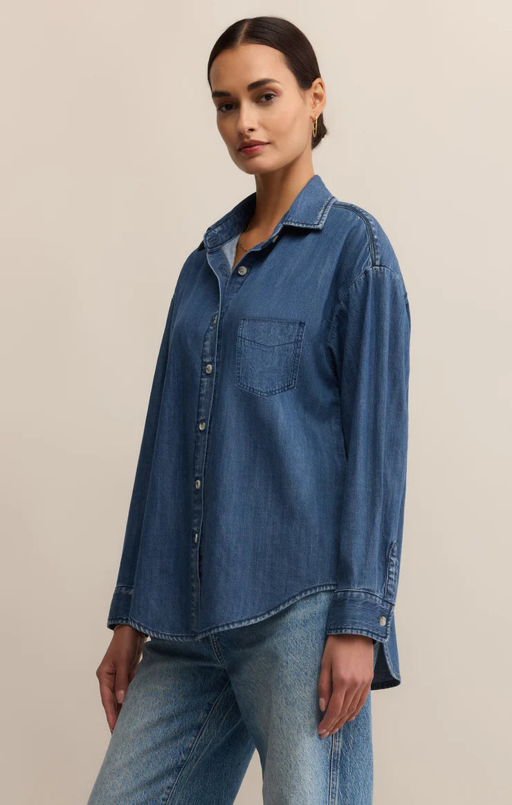 Woman wearing a blue denim shirt and jeans on a beige background