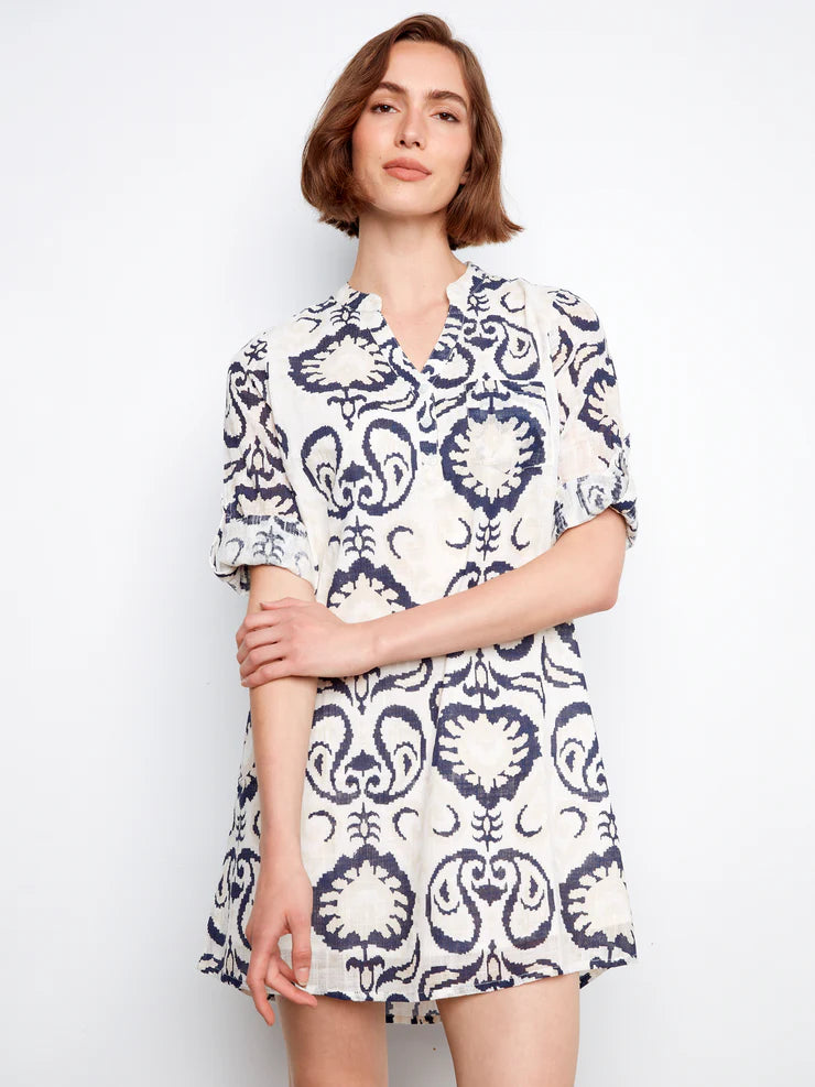 Woman wearing a white dress with blue pattern on a plain background