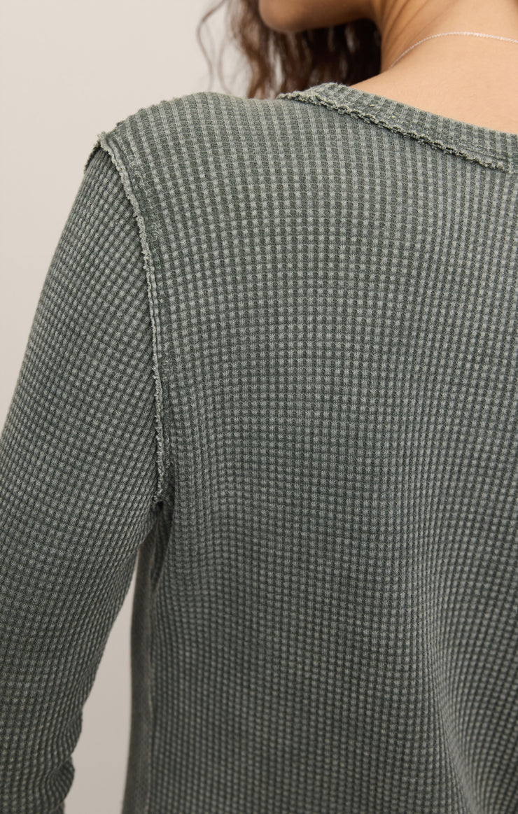 Close-up of a person wearing a textured green sweater against a neutral background