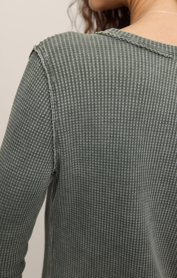 Close-up of a person wearing a textured green sweater against a neutral background