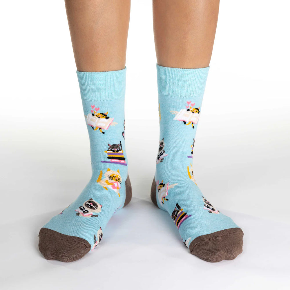 Light blue socks with cat designs worn by a person on a white background