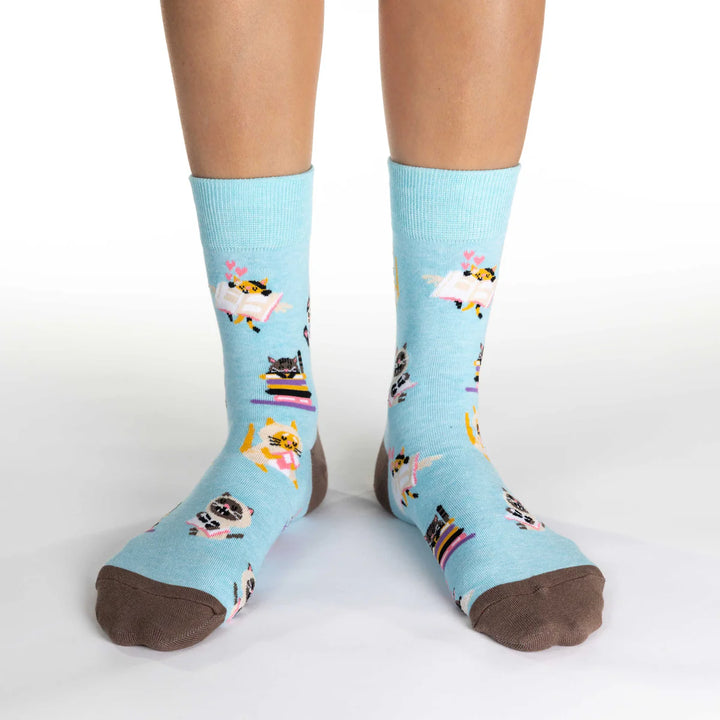 Light blue socks with cat designs worn by a person on a white background