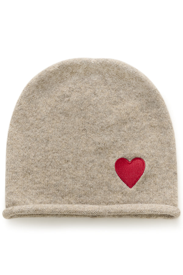 A light beige knit beanie hat featuring a small, embroidered red heart on the side, displayed against a clean white background.