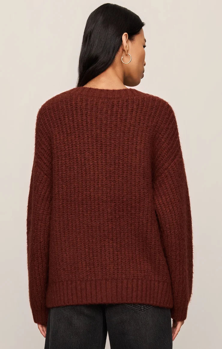 Person wearing a maroon sweater against a beige background