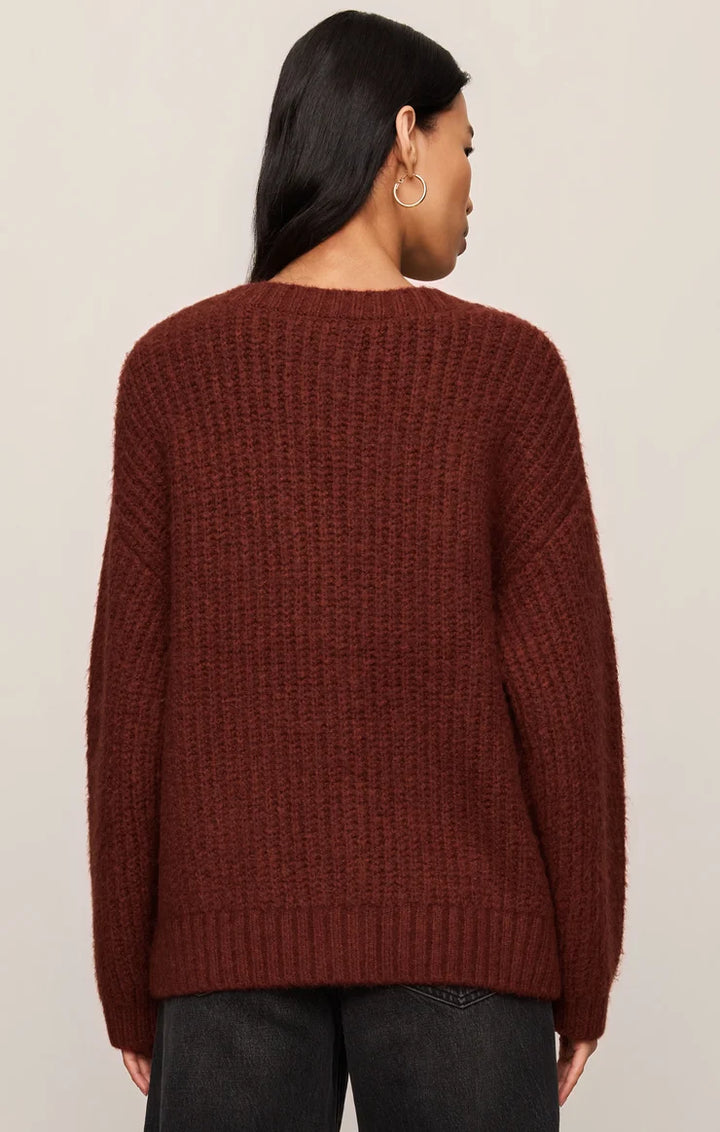 Person wearing a maroon sweater against a beige background