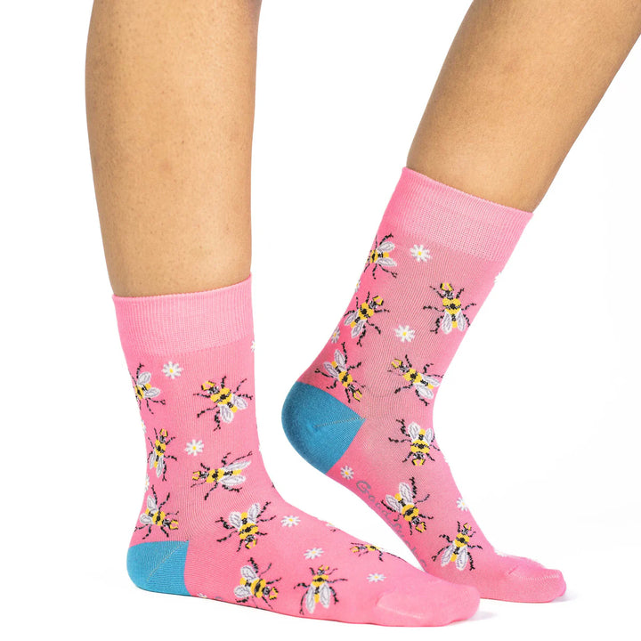 Pink socks with bee pattern worn by a person on a white background