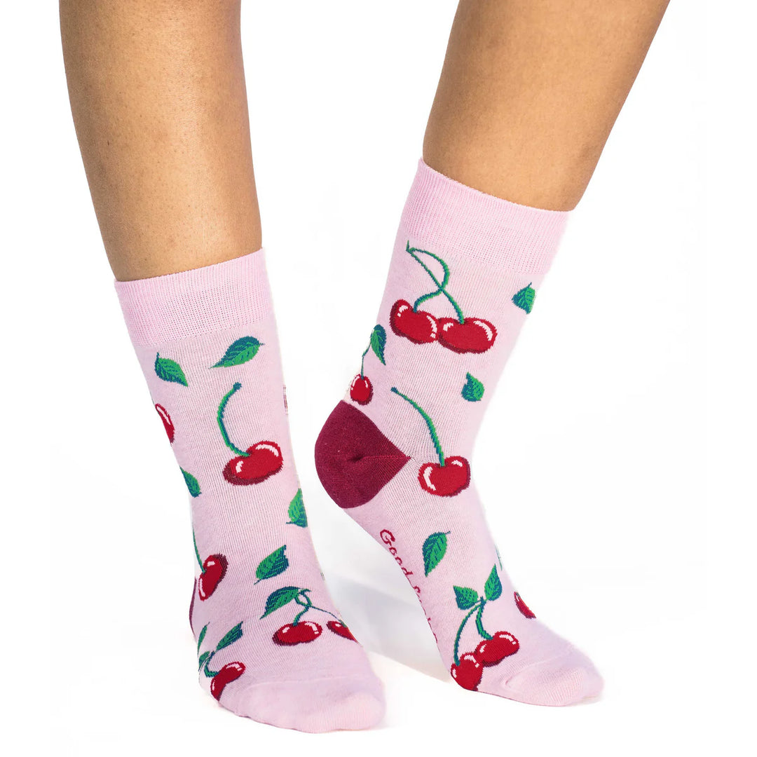 Pink socks with cherry design worn by a person on a white background
