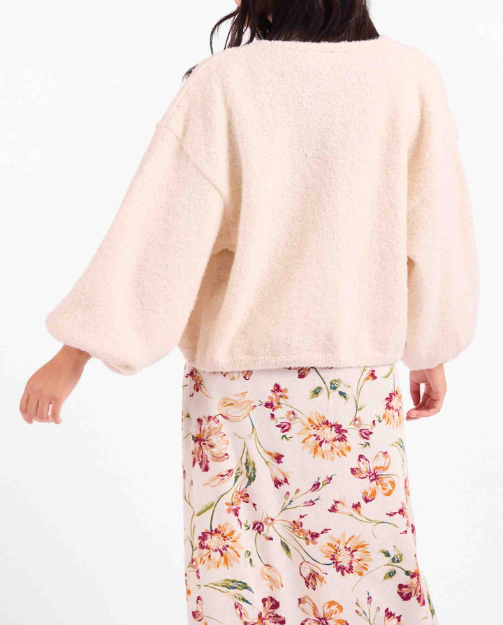 Person wearing a light pink top and floral skirt on a white background