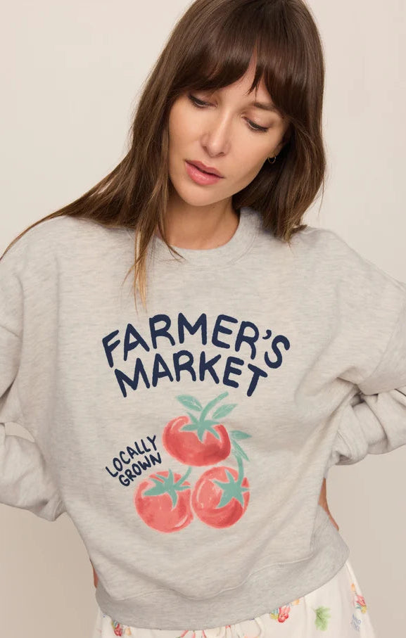 A woman wearing a light gray heather crewneck sweatshirt with a &