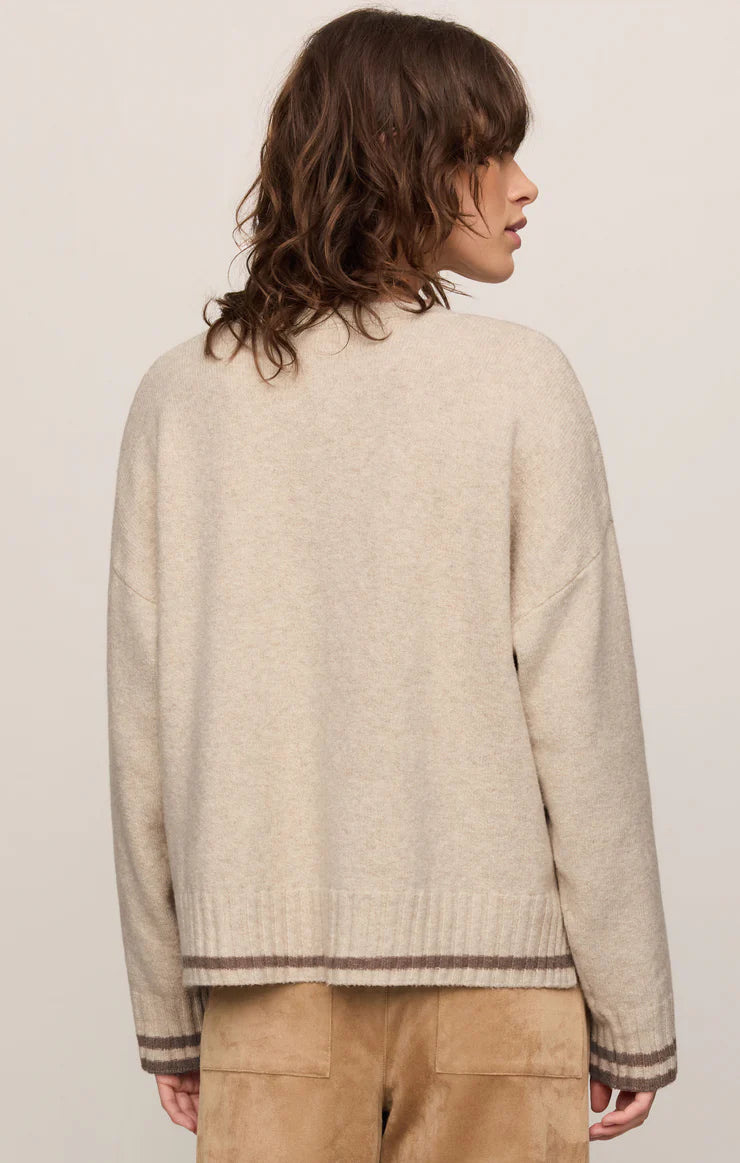 Person wearing a beige sweater with a plain background