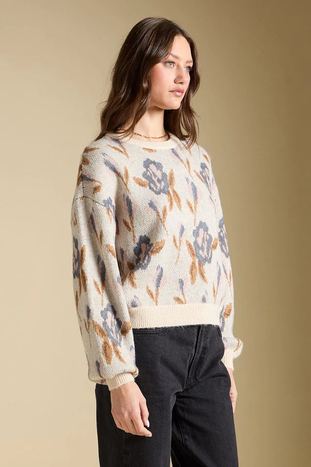 Woman wearing a floral-patterned sweater against a beige background