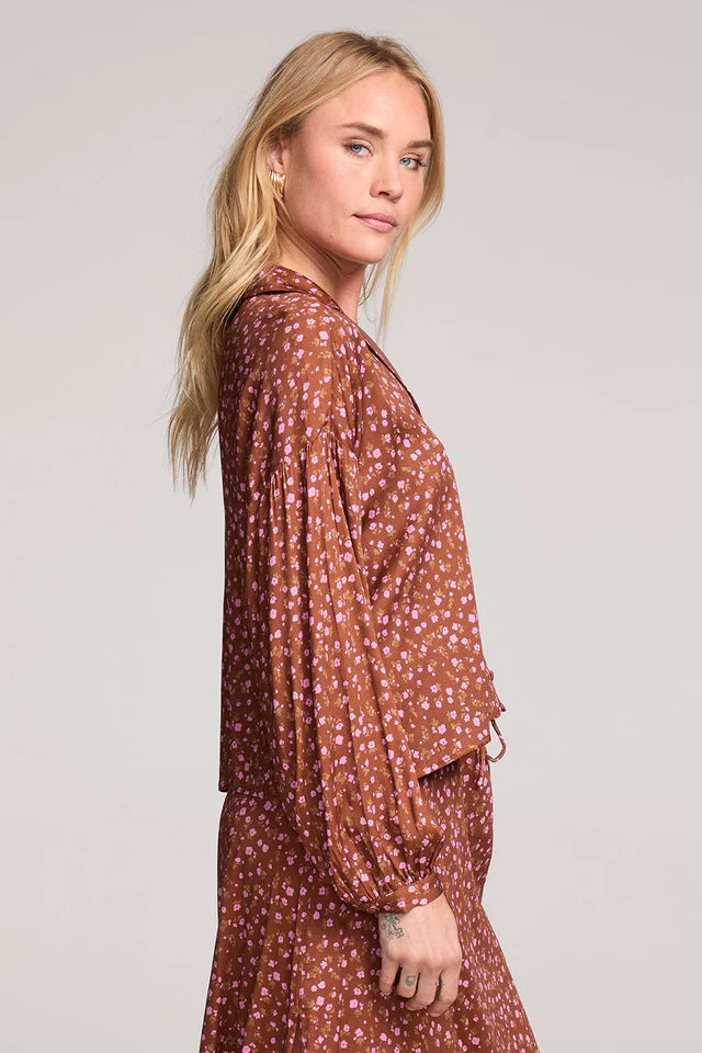 Woman wearing a brown patterned dress against a plain background