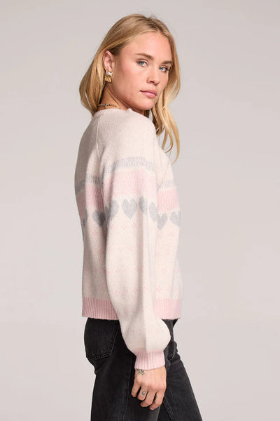Woman wearing a light pink sweater with a subtle pattern on a plain background