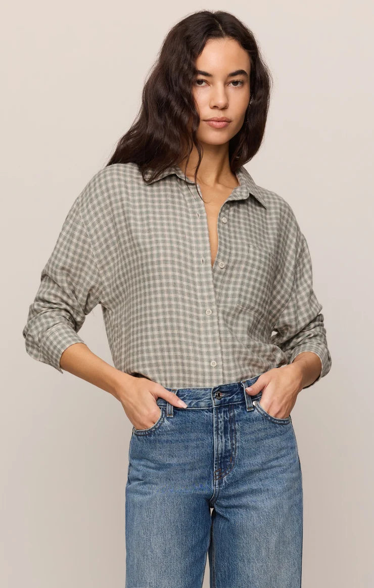 Woman wearing a plaid shirt and jeans against a plain background