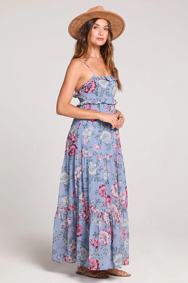 Woman wearing a floral dress and hat on a plain background