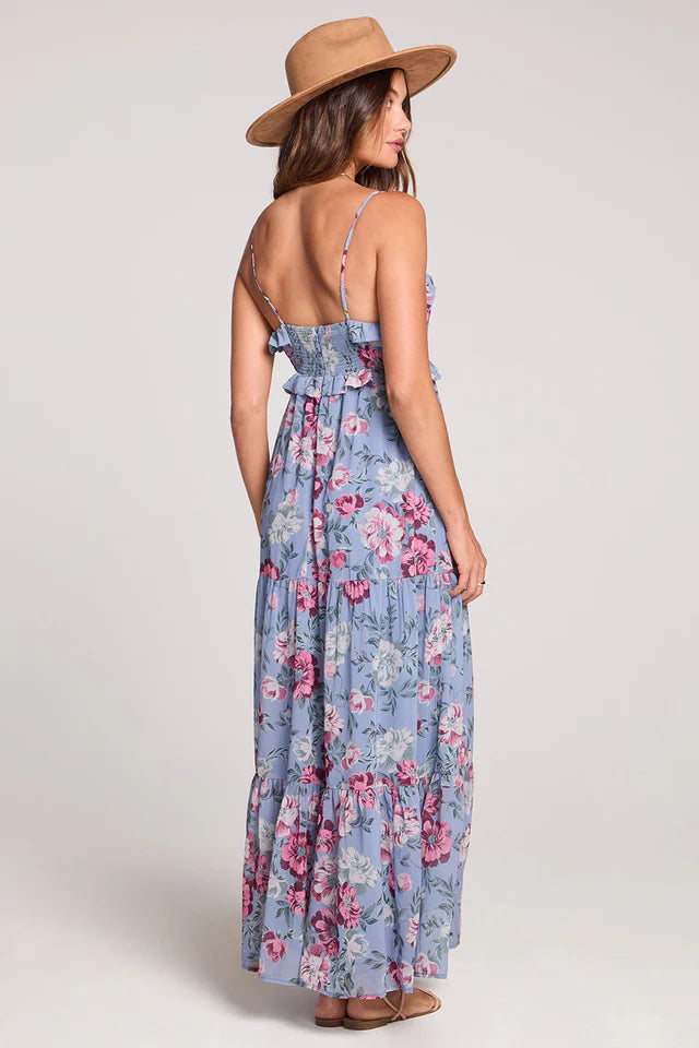 Woman wearing a floral dress and wide-brimmed hat on a plain background
