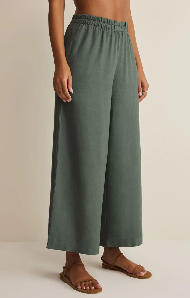 Person wearing green wide-leg pants on a beige background