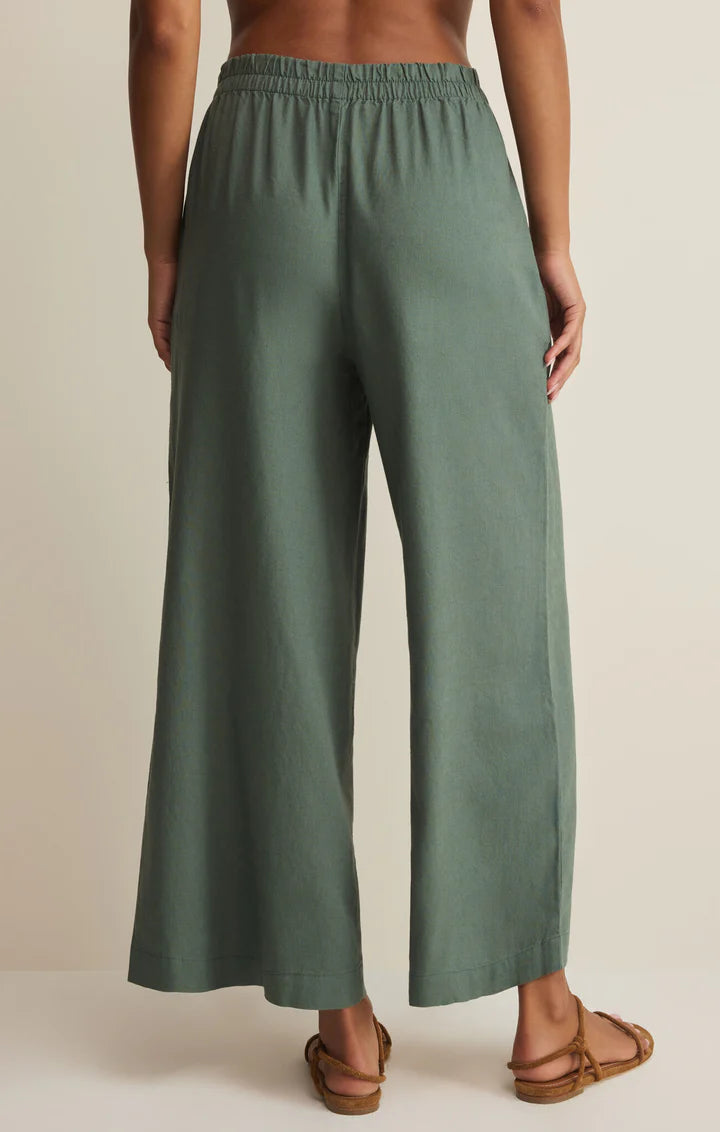 Green wide-leg pants worn by a person on a beige background