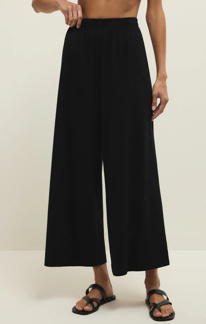 Person wearing black wide-leg pants on a plain background