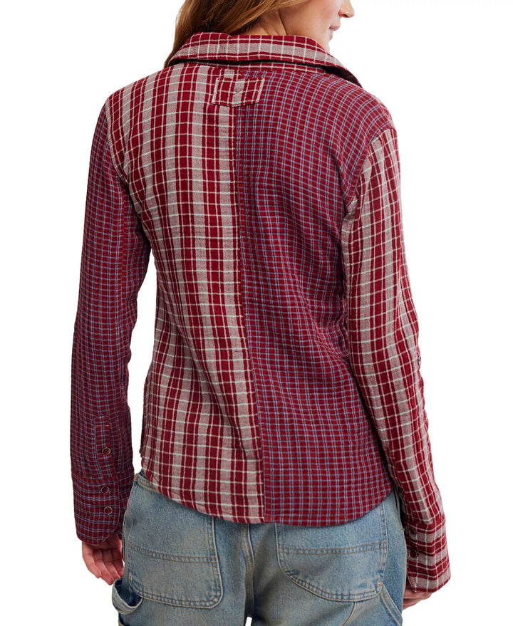 A woman shown from the back wearing a red and beige plaid long-sleeve button-up shirt with light blue jeans, against a plain white background.