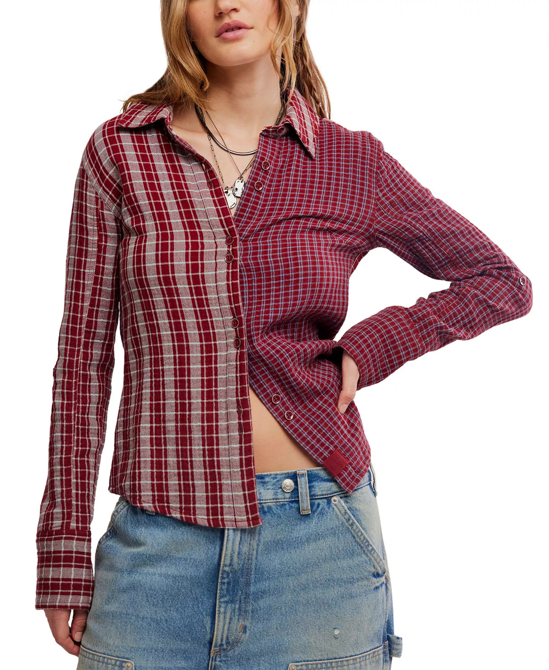 A woman wearing a red and beige plaid button-up shirt tucked into blue jeans, shown from the neck down against a plain white background.