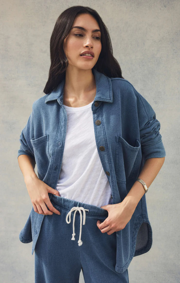 Woman wearing a blue denim shirt and pants against a gray background