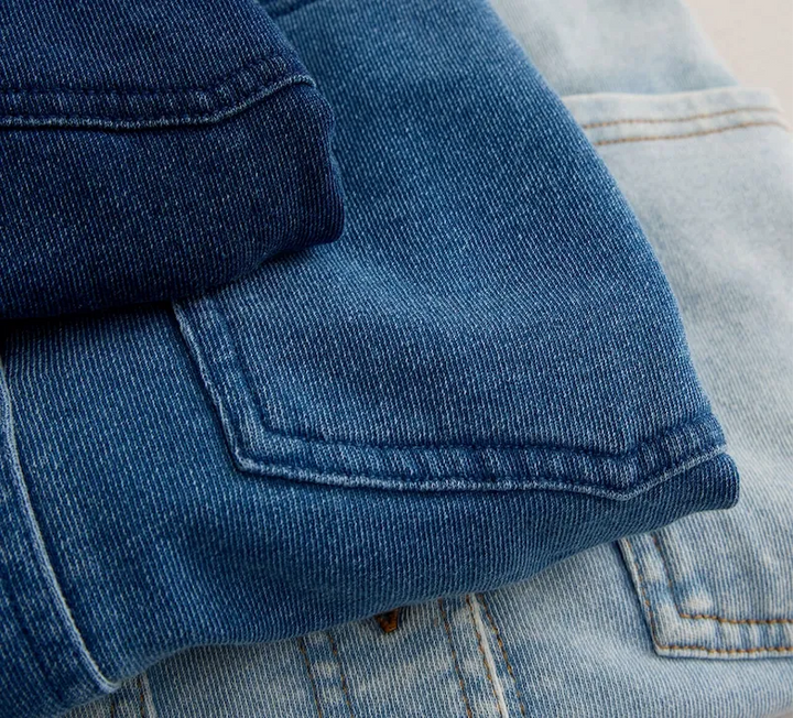 Stack of folded blue jeans on a light background