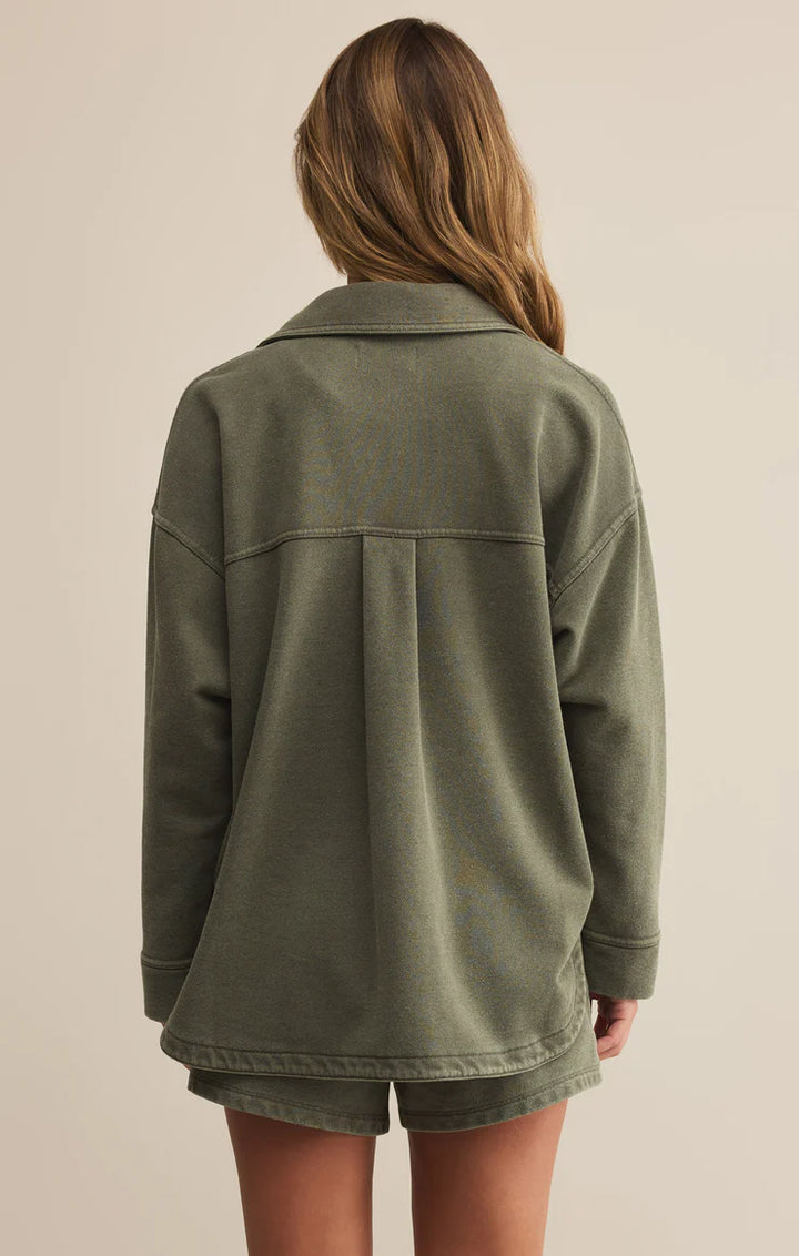 Person wearing a green jacket on a beige background