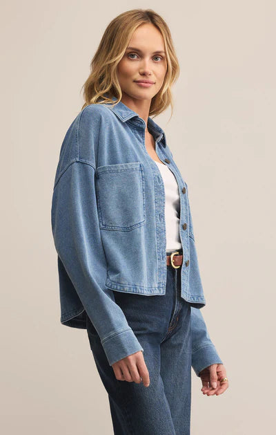 Woman wearing a blue denim jacket and jeans on a beige background
