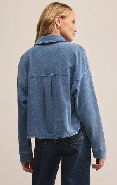 Woman wearing a blue denim jacket on a beige background