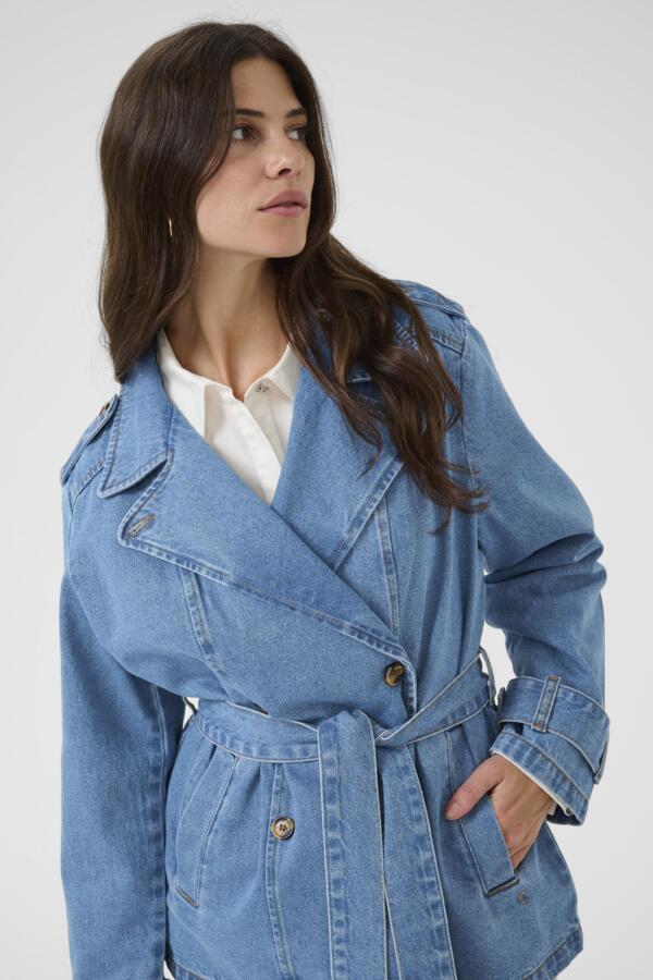 Woman wearing a blue denim trench coat against a white background