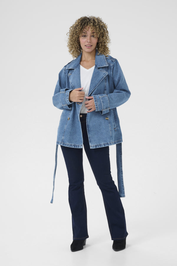 Woman wearing a blue denim jacket and dark jeans on a white background