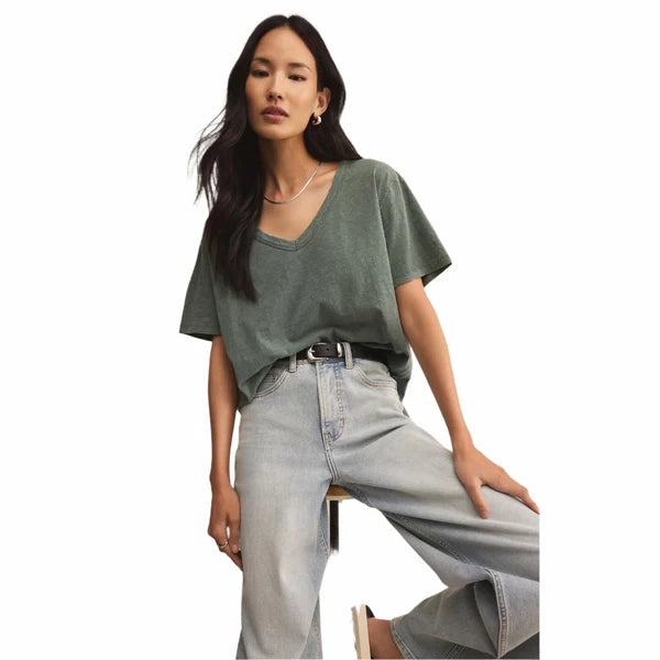 Woman wearing a green oversized t-shirt and light blue jeans on a white background