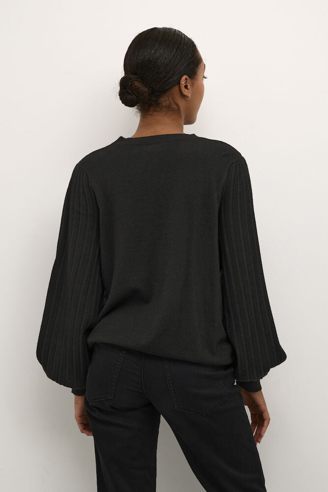 Person wearing a black long-sleeve top and pants against a white background