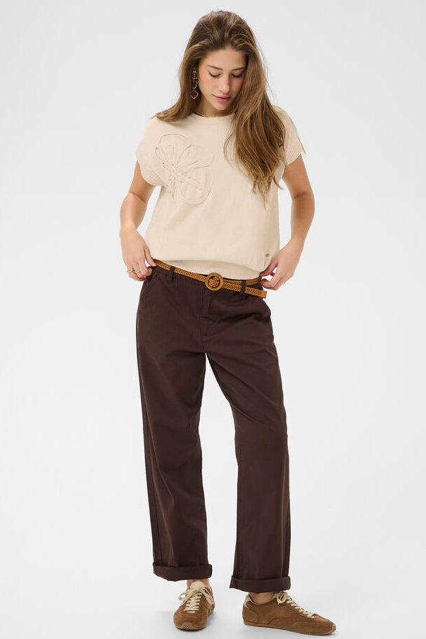 Woman wearing a beige sweater and brown pants on a white background