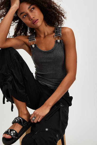 Woman wearing a black tank top and black pants with a white background