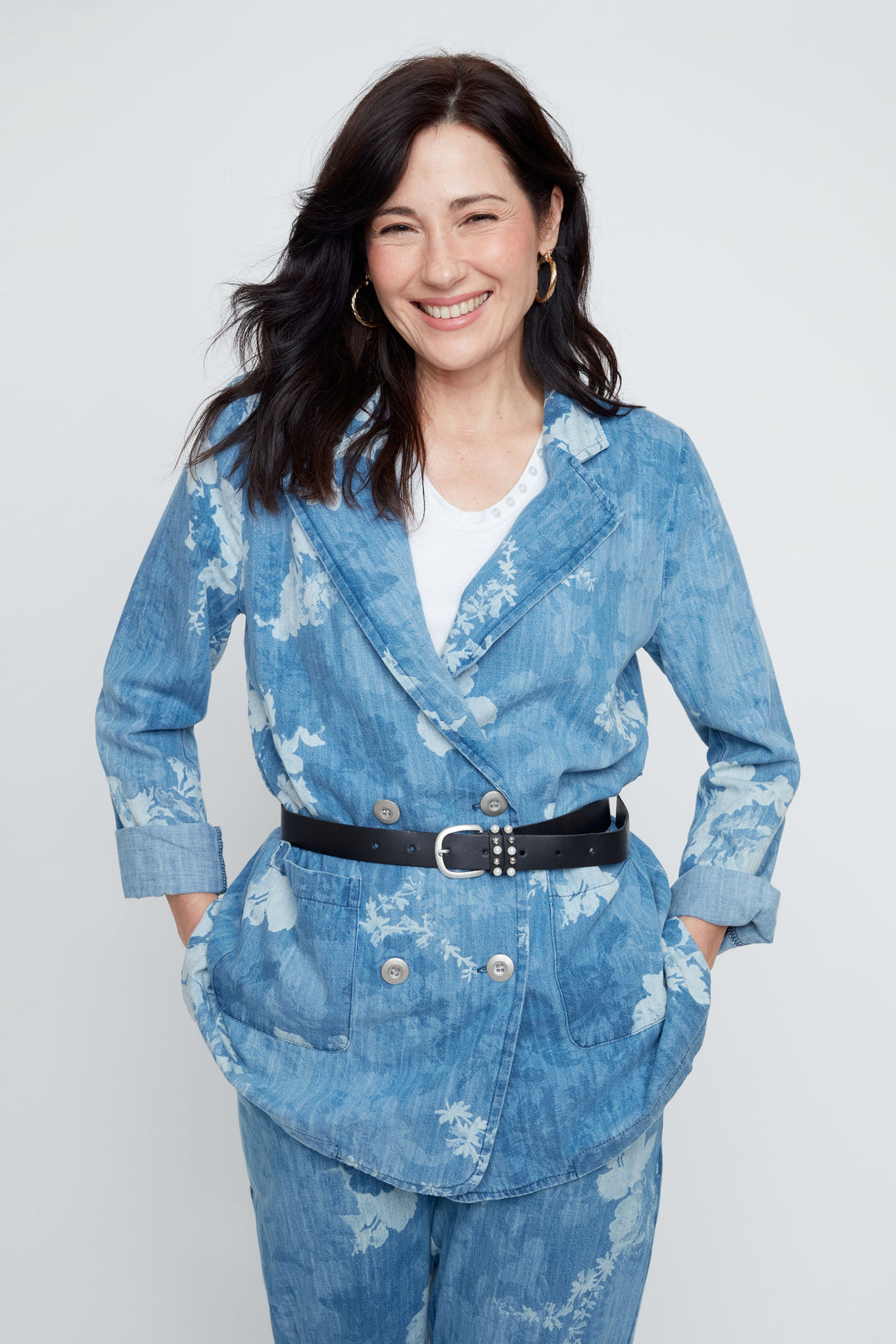 Woman wearing a blue distressed denim suit with a white background