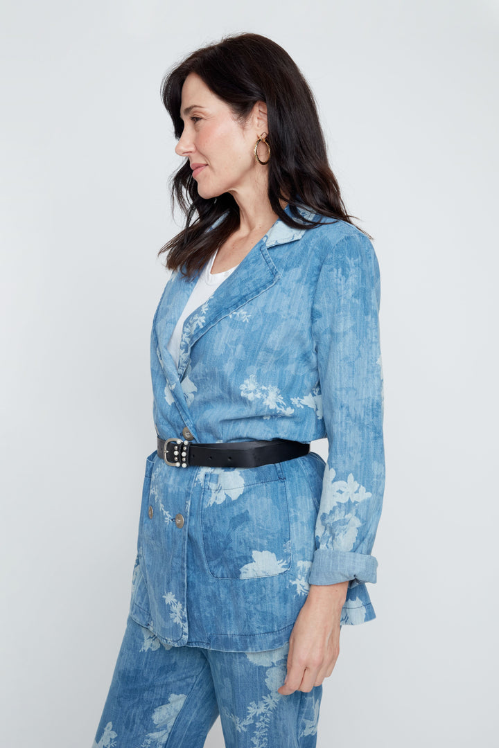 Woman wearing a blue floral blazer and pants with a white background