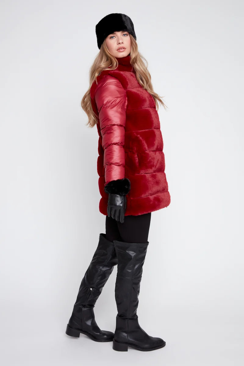 Woman wearing a red puffer coat, black gloves, and black boots on a white background