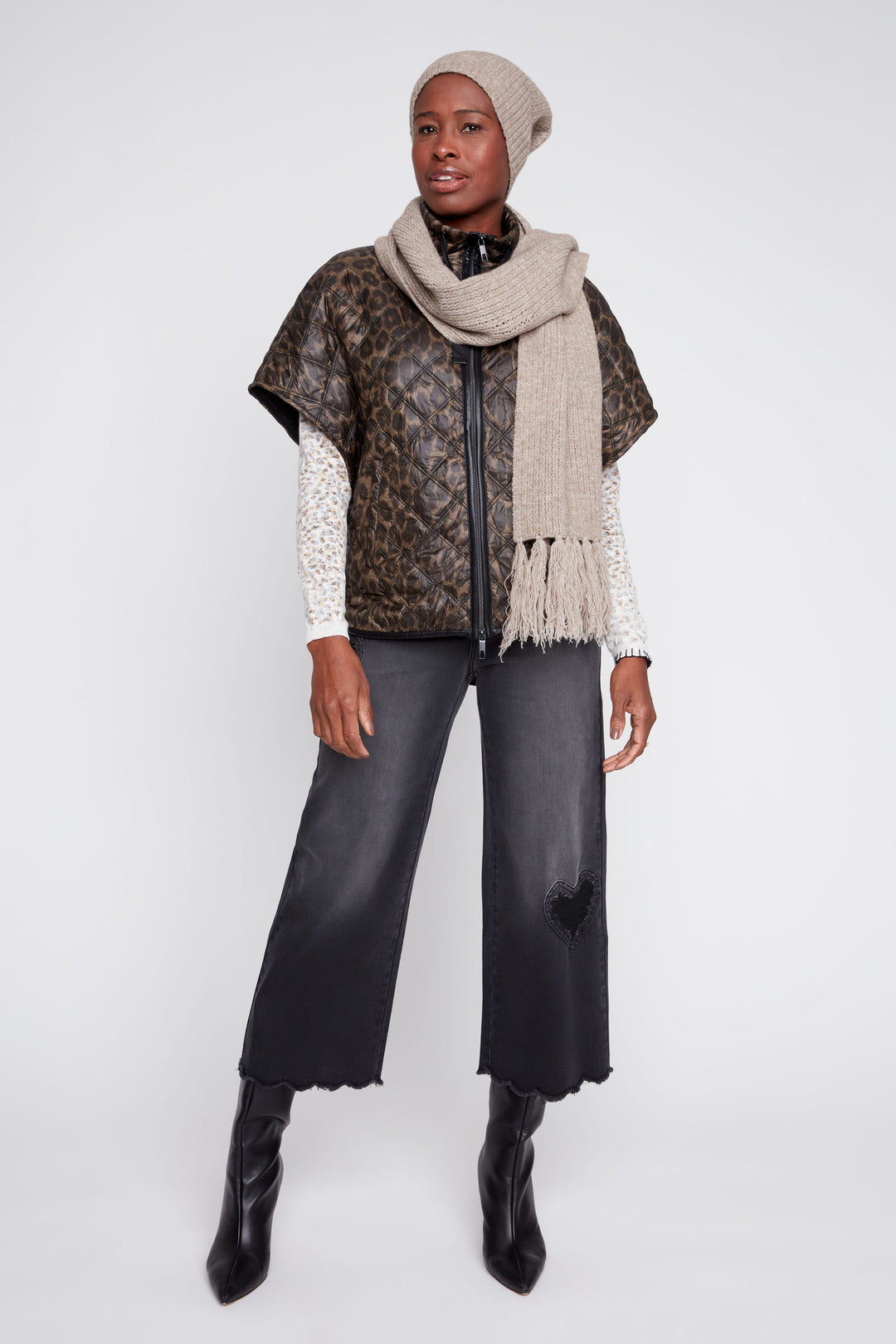 Person wearing a patterned vest, scarf, and pants on a white background