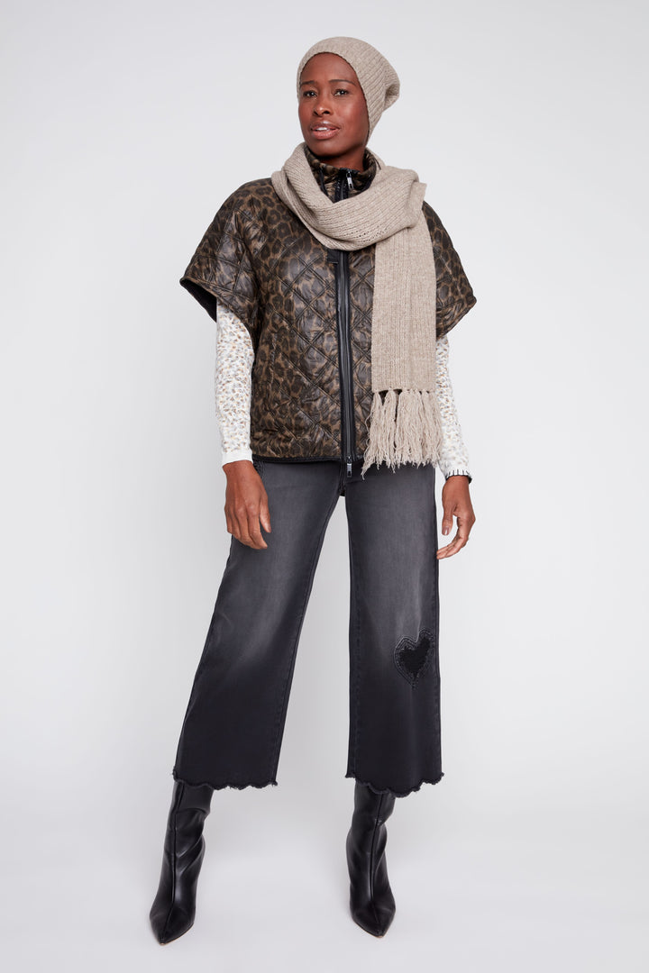 Person wearing a patterned vest, scarf, and pants on a white background